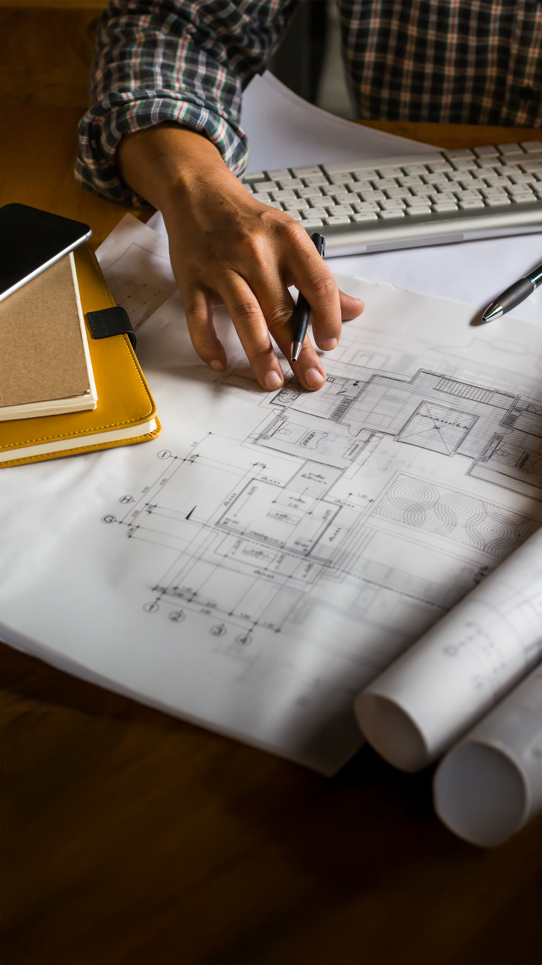 Architecte analysant des plans de construction de maison individuelle avec des outils de travail sur un bureau