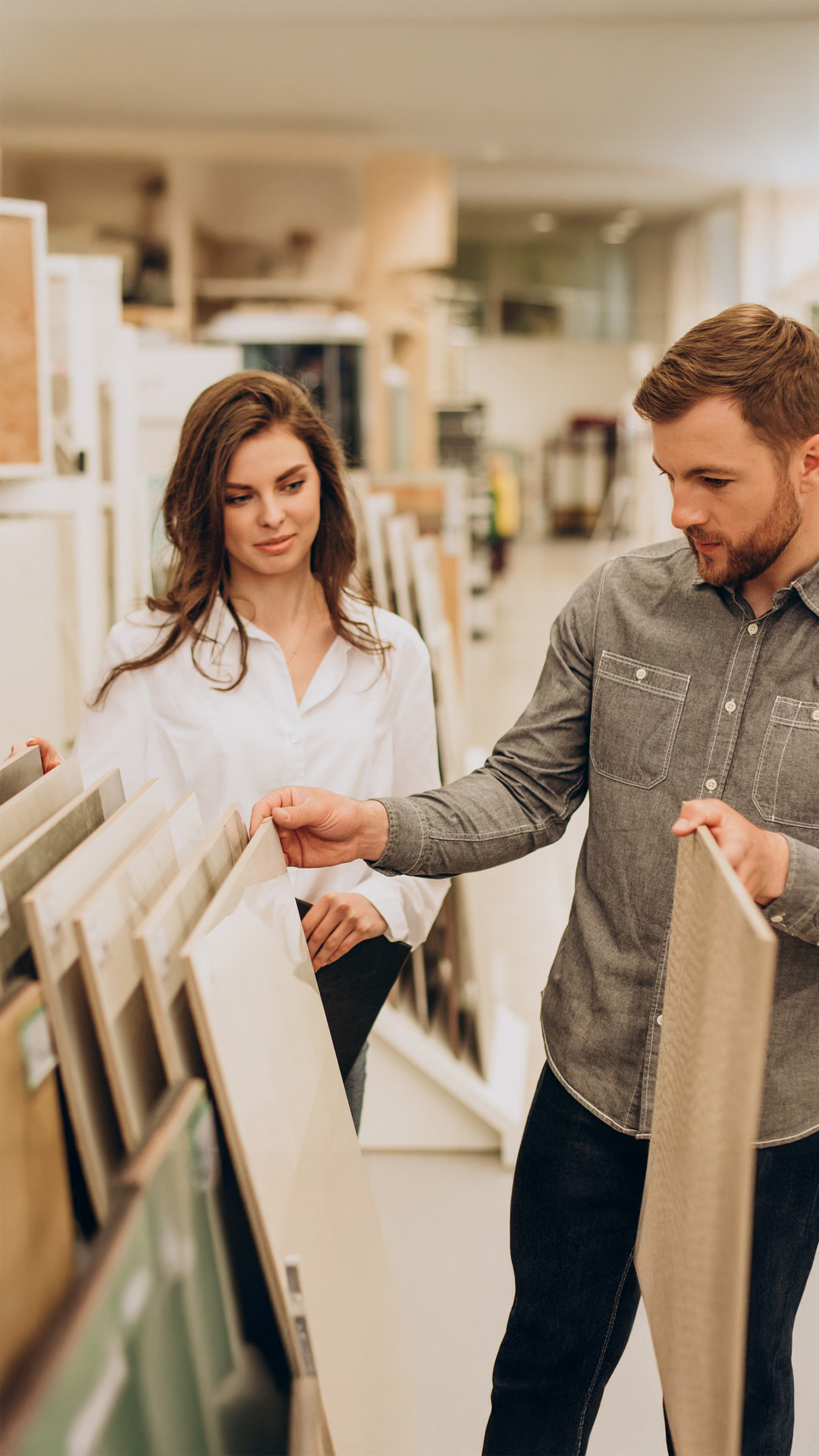 Couple consultant des échantillons de carrelage dans un magasin de matériaux pour la construction ou la rénovation de leur maison individuelle